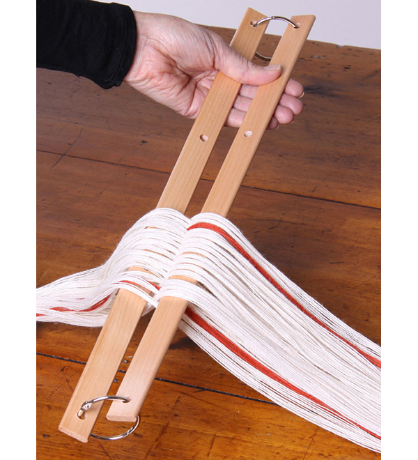 a person holding two warp sticks attached by a metal ring, separating a white and red warp